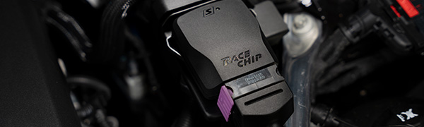 Primo piano della centralina RaceChip S nel vano motore, alloggiamento nero con logo RaceChip, etichetta prodotto e connettore originale viola.